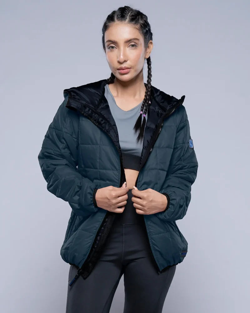 Woman wearing a dark blue puffer jacket on a gray background