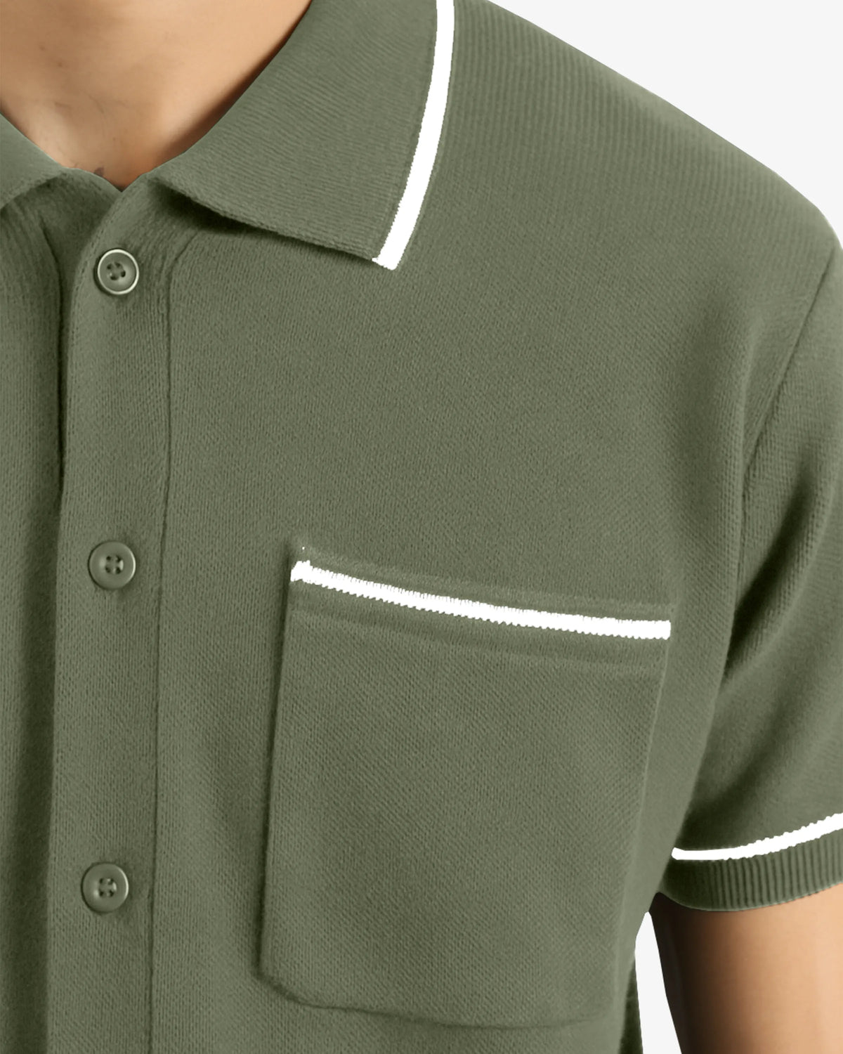 Green polo shirt with white trim on a neutral background