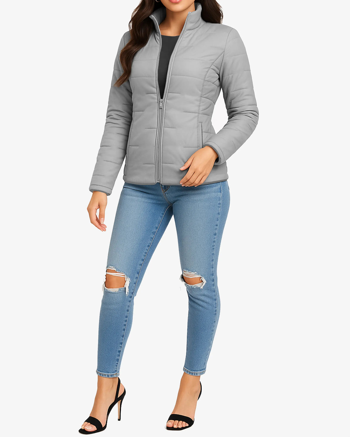 Woman wearing a gray quilted jacket and light blue jeans with ripped knees on a white background