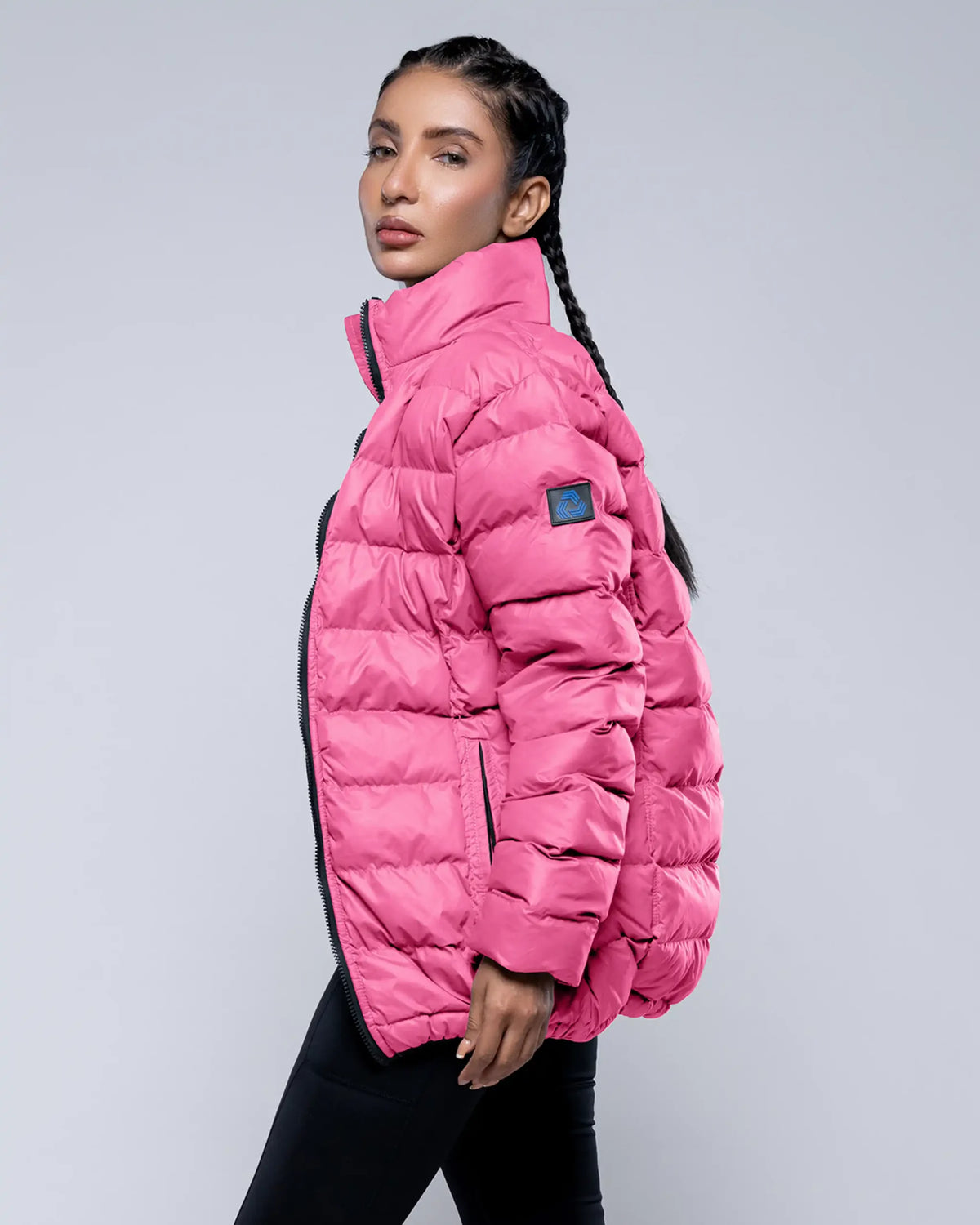 Person wearing a pink puffer jacket on a gray background