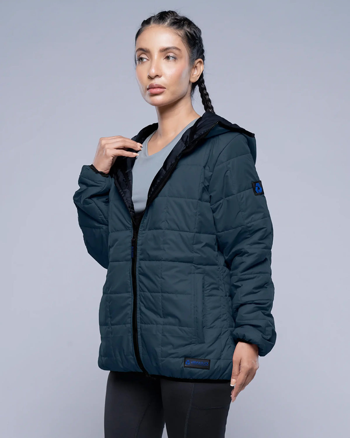 Woman wearing a dark blue puffer jacket on a gray background