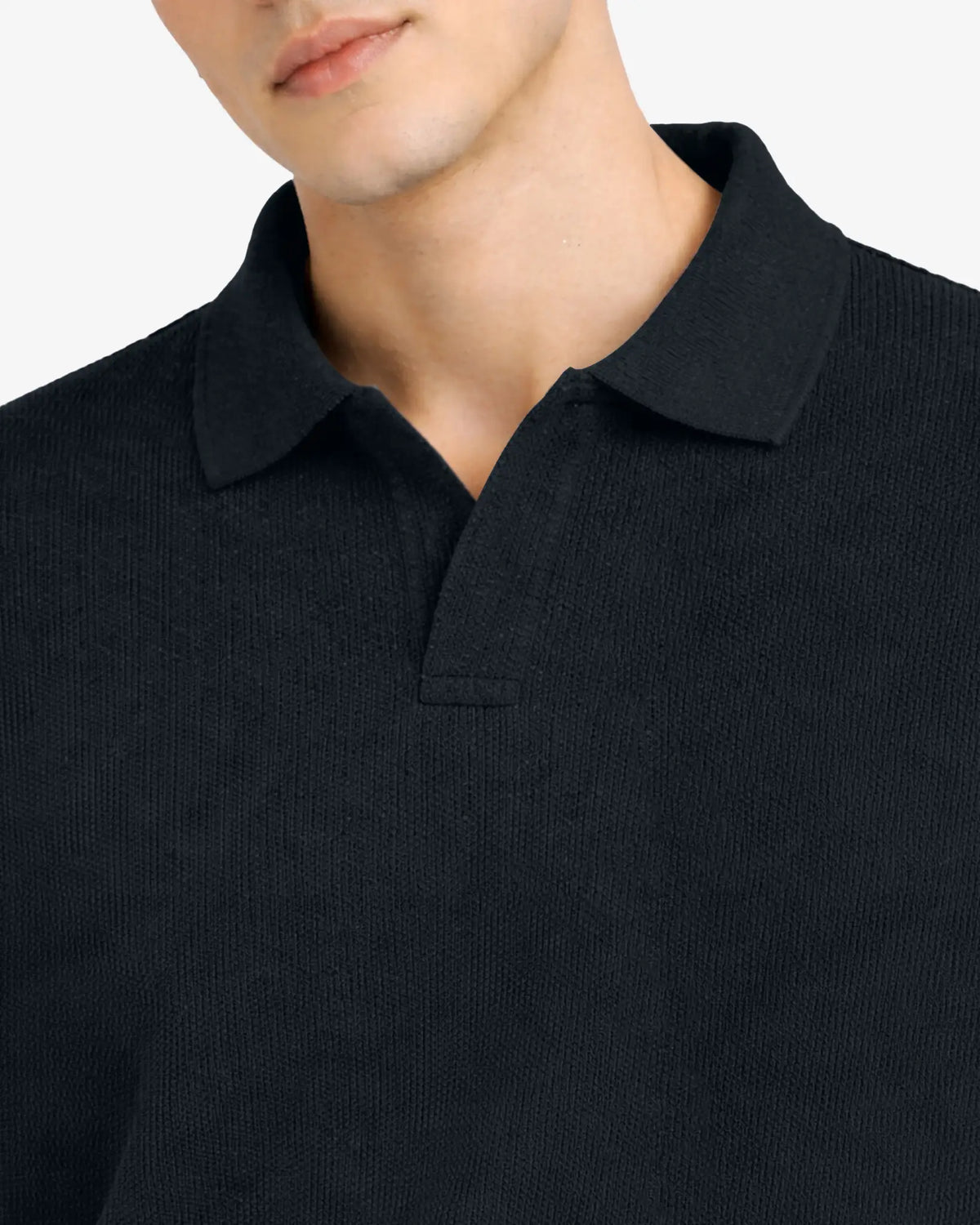 Close-up of a person wearing a black polo shirt with a plain background