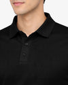 Close-up of a person wearing a black polo shirt with a blurred background