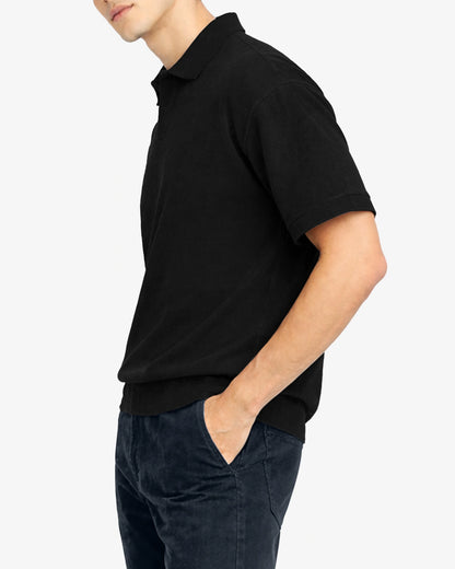 Person wearing a black polo shirt and dark pants on a white background