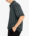 Person wearing a dark green polo shirt with white stripes on a white background