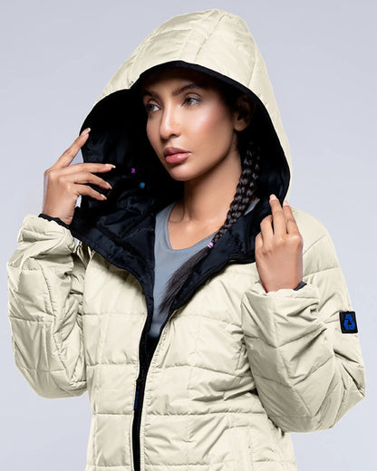 Woman wearing a beige puffer jacket with a hood against a light gray background