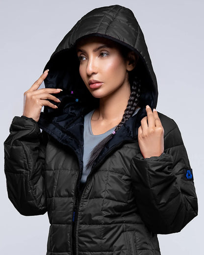 Person wearing a black puffer jacket with a hood against a gray background