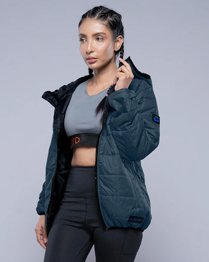 Woman wearing a dark green jacket over athletic wear on a gray background