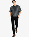 Man wearing a striped polo shirt and black pants on a white background