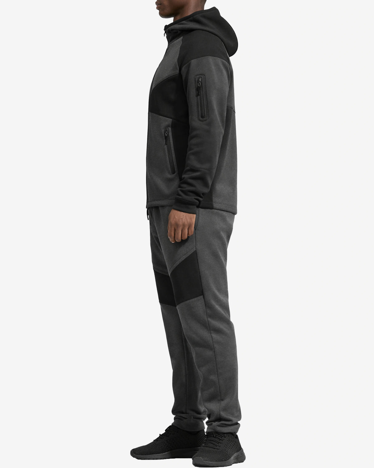 Person wearing a gray and black tracksuit on a white background