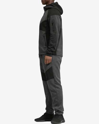 Person wearing a gray and black tracksuit on a white background