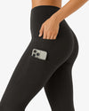 Black leggings with a pocket holding a phone on a white background