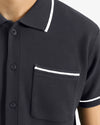 Black polo shirt with white trim on collar and pocket