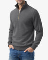 Man wearing a gray half-zip sweater and blue jeans on a white background