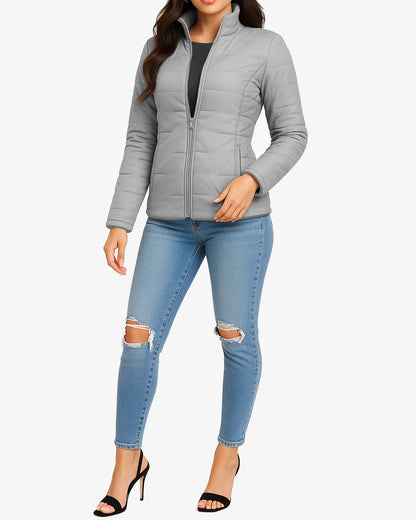 Woman wearing a gray quilted jacket and light blue jeans with ripped knees on a white background