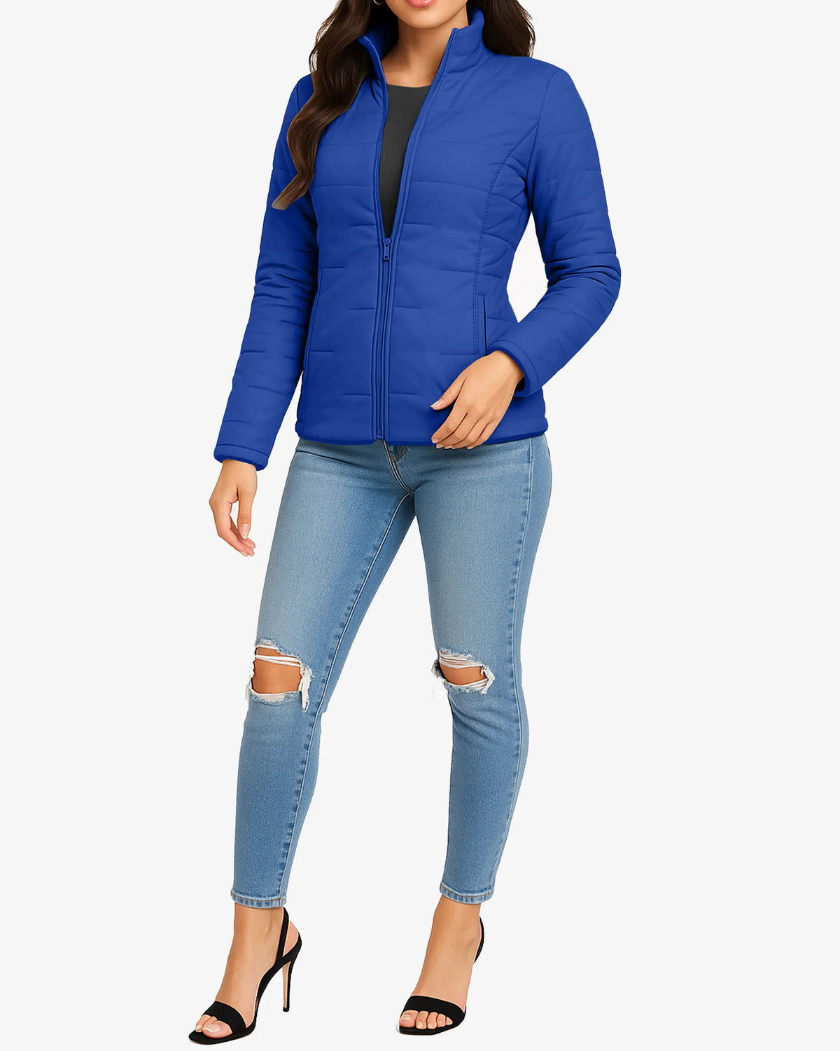 Woman wearing a blue puffer jacket and ripped jeans on a white background