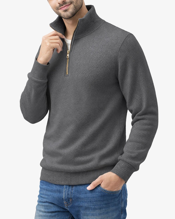 Man wearing a gray quarter-zip sweater and blue jeans on a white background