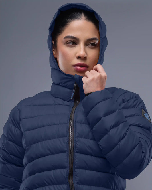 Woman wearing a blue puffer jacket against a gray background