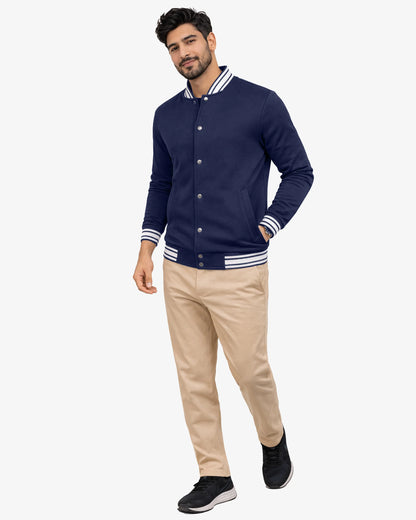 Man wearing a navy blue varsity jacket with white stripes on a white background