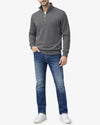 Man wearing a gray quarter-zip sweater and blue jeans on a white background