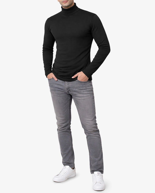 Person wearing a black turtleneck and gray jeans on a white background