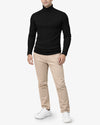 Person wearing a black turtleneck sweater, beige pants, and white sneakers on a white background