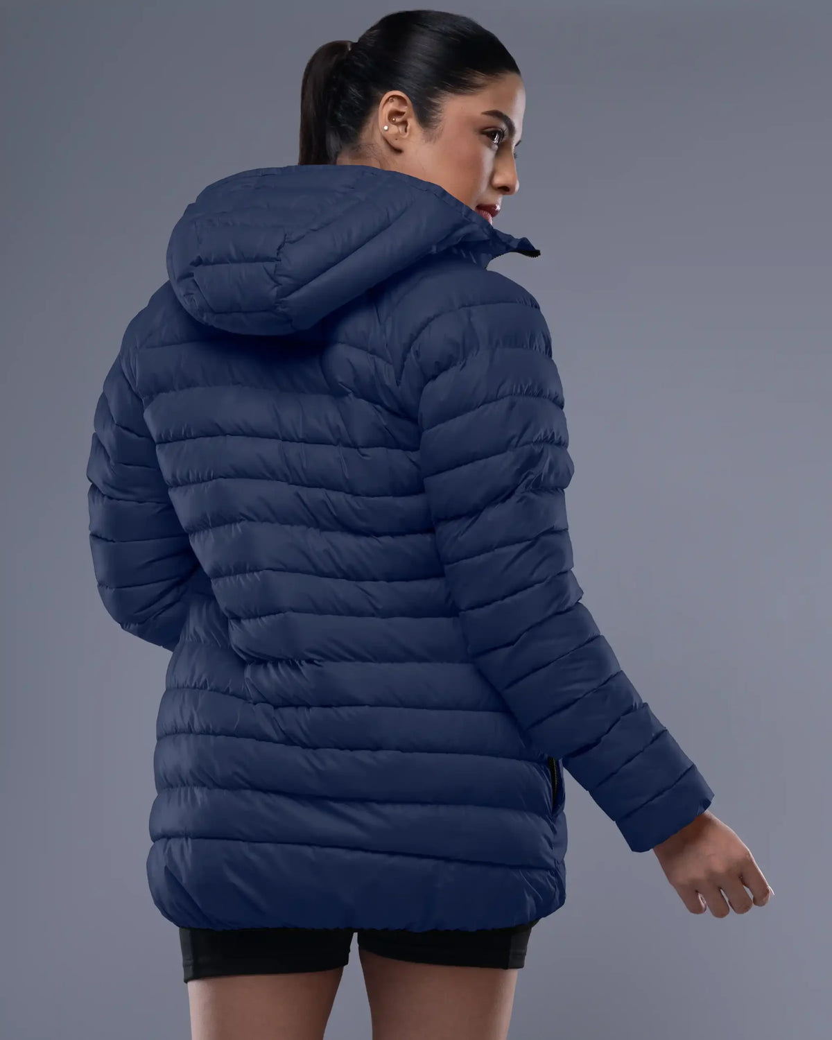 Woman wearing a blue puffer jacket against a gray background