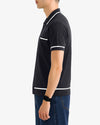 Person wearing a black polo shirt with white accents on a plain background