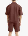 Person wearing a brown polo shirt and shorts set on a white background
