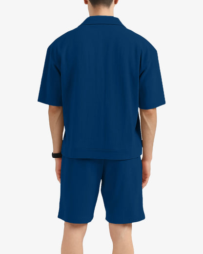 Person wearing a blue polo shirt and shorts set on a white background