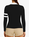 Black long-sleeve top with white stripes on sleeves and beige shorts against a light gray background