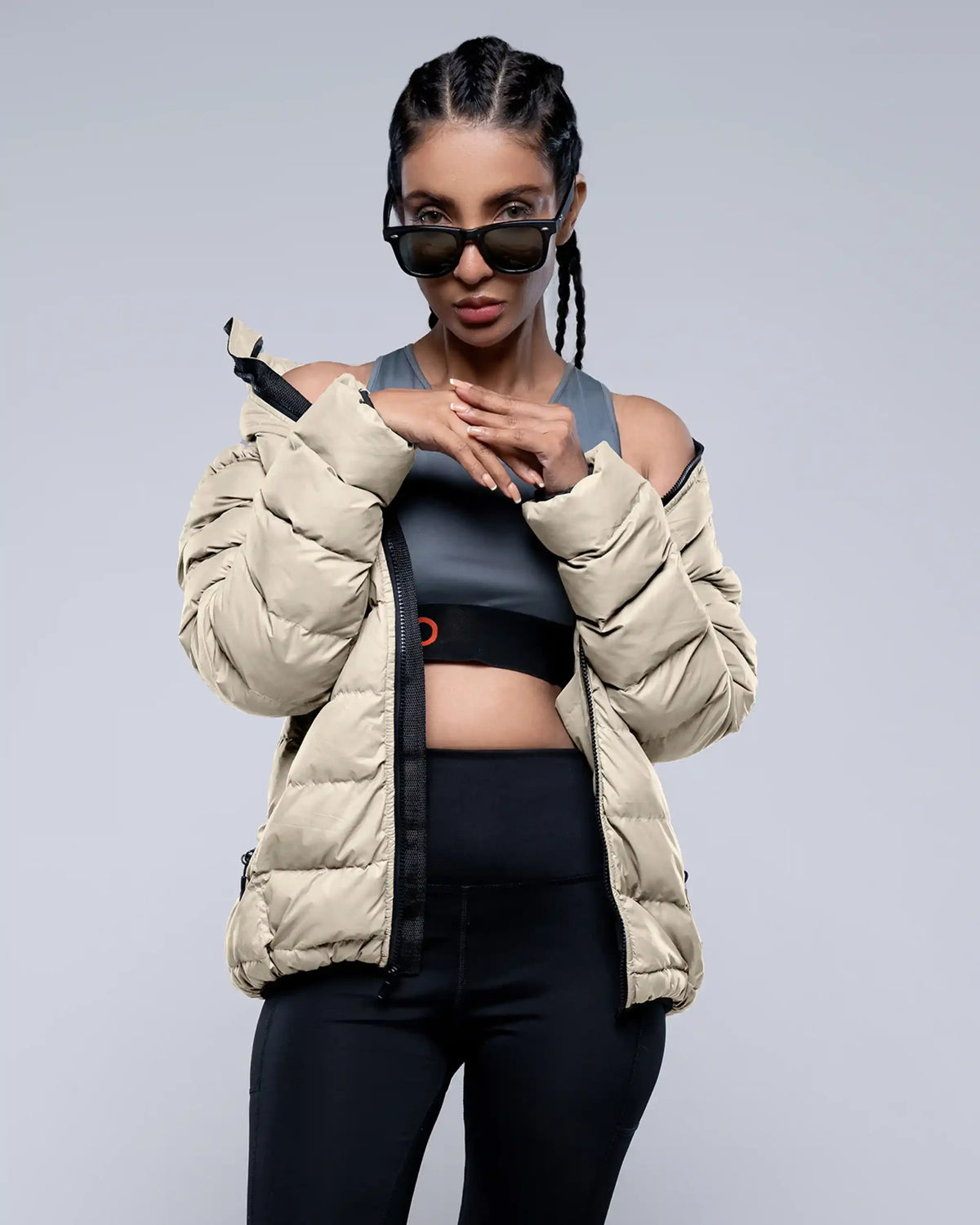 Person wearing a beige puffer jacket and black athletic outfit on a gray background