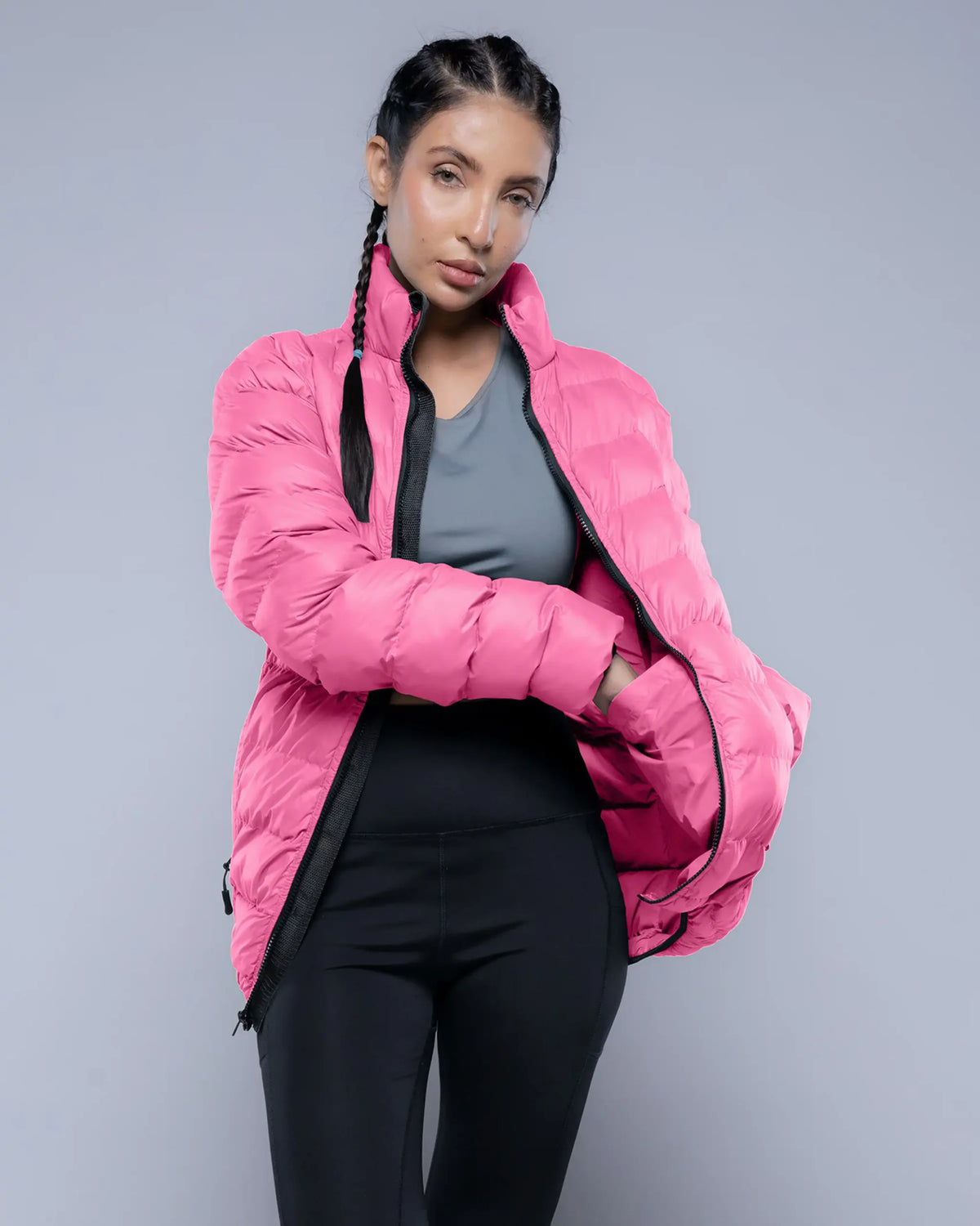 Person wearing a pink puffer jacket on a gray background